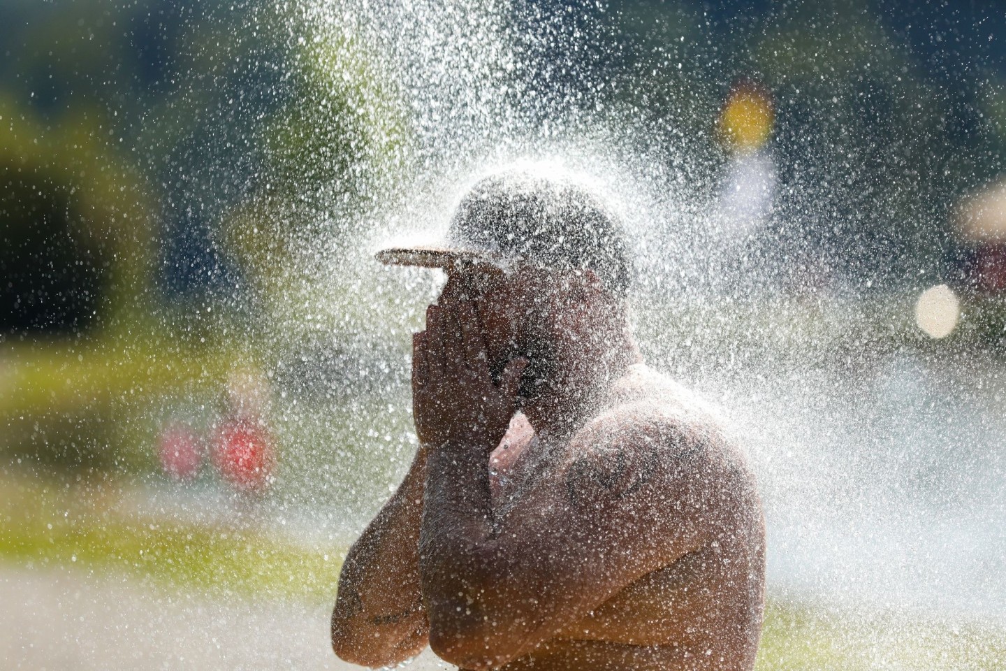 Ein Mann erfrischt sich an einem Badesee unter einer kalten Dusche.