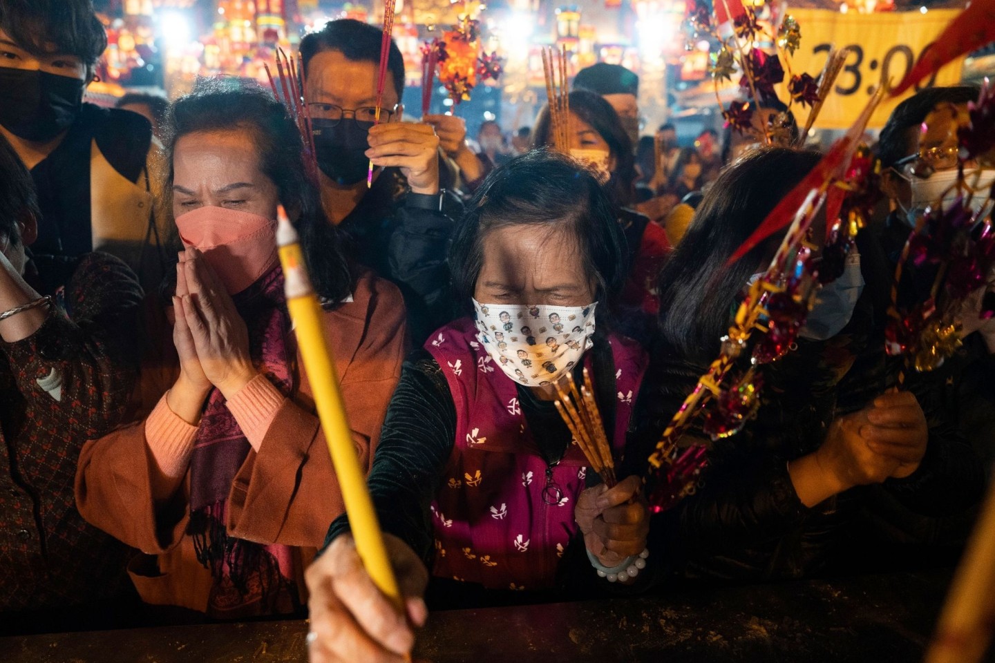 Gläubige mit Mund-Nasen-Schutz verbrennen ihre ersten Räucherstäbchen, während sie im Wong-Tai-Sin-Tempel in Hongkong das Neujahrsfest feiern.