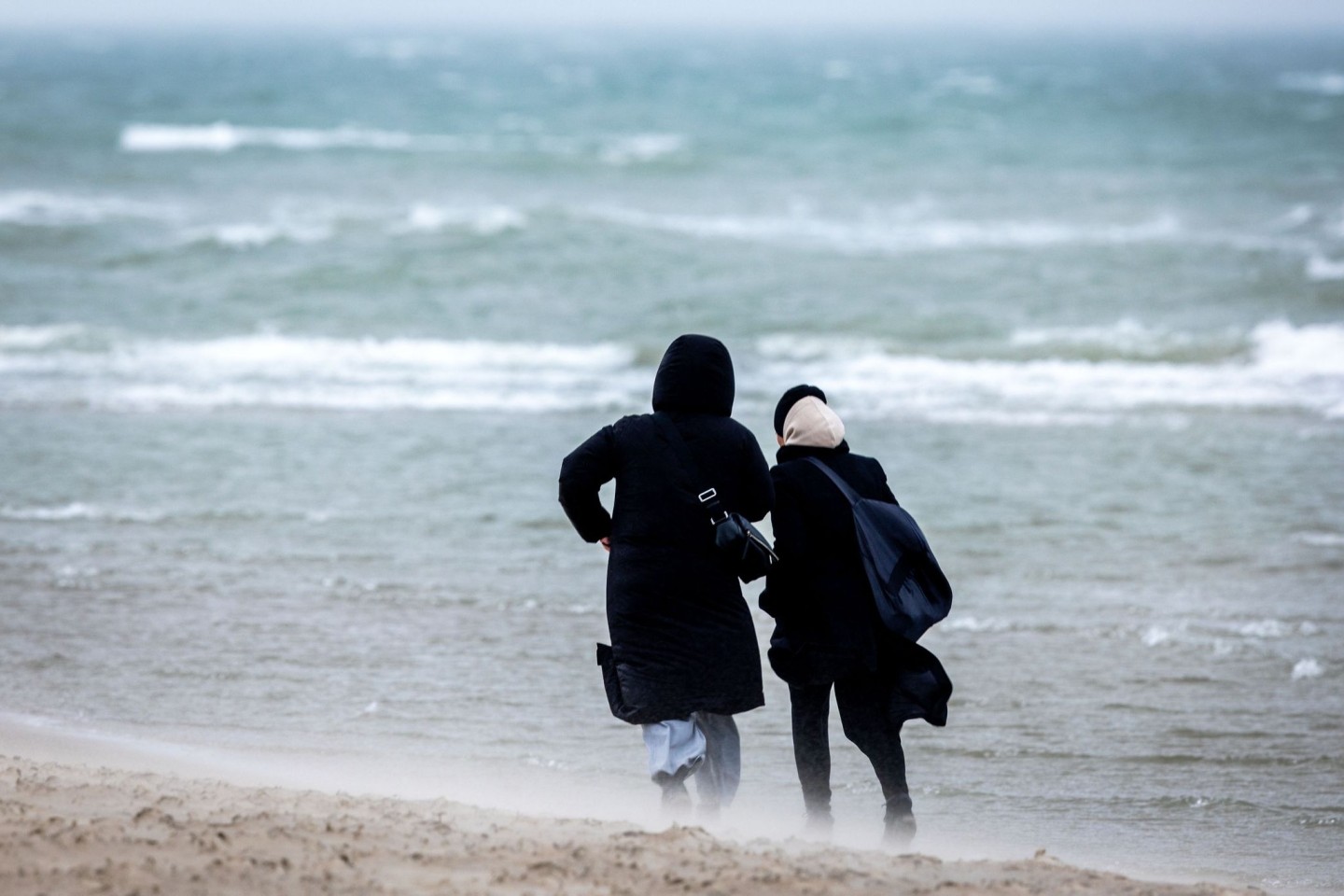 Spaziergänger trotzen dem regnerischen Wetter an der Ostseeküste nahe Rostock.