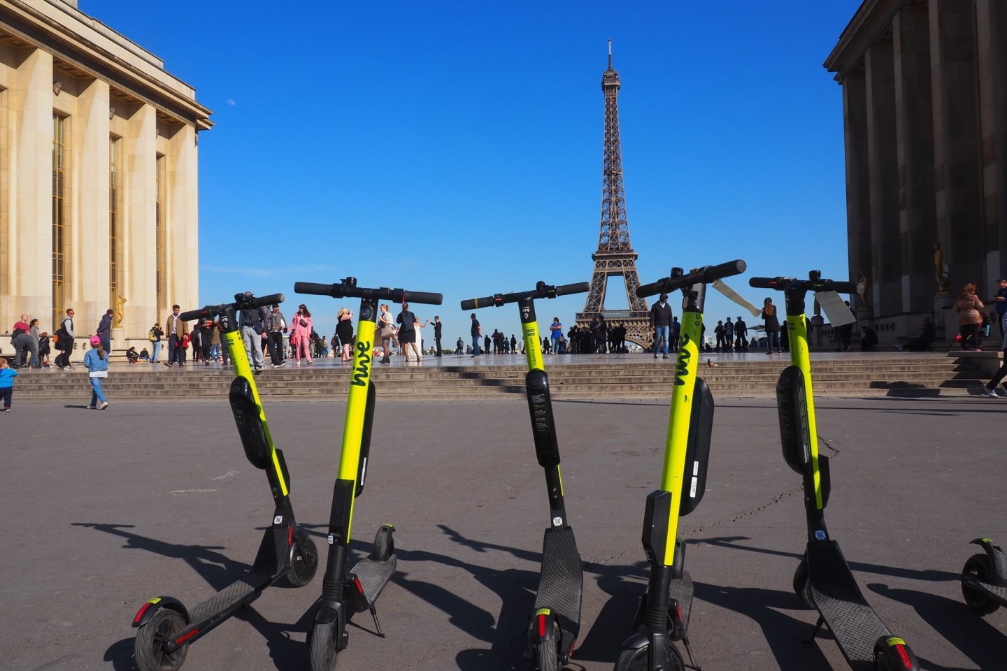 E-Tretroller zum Mieten stehen auf der Place du Trocadero in Paris, im Hintergrund ist der Eiffelturm zu sehen.