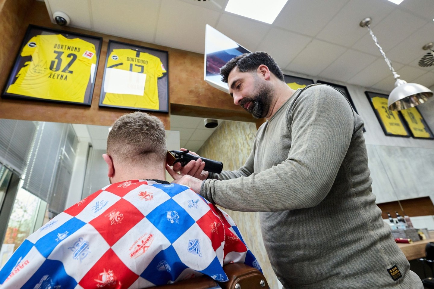 Friseur Taner Dogan schneidet in seinem Salon in einer Netto-Filiale einem Kunden die Haare.