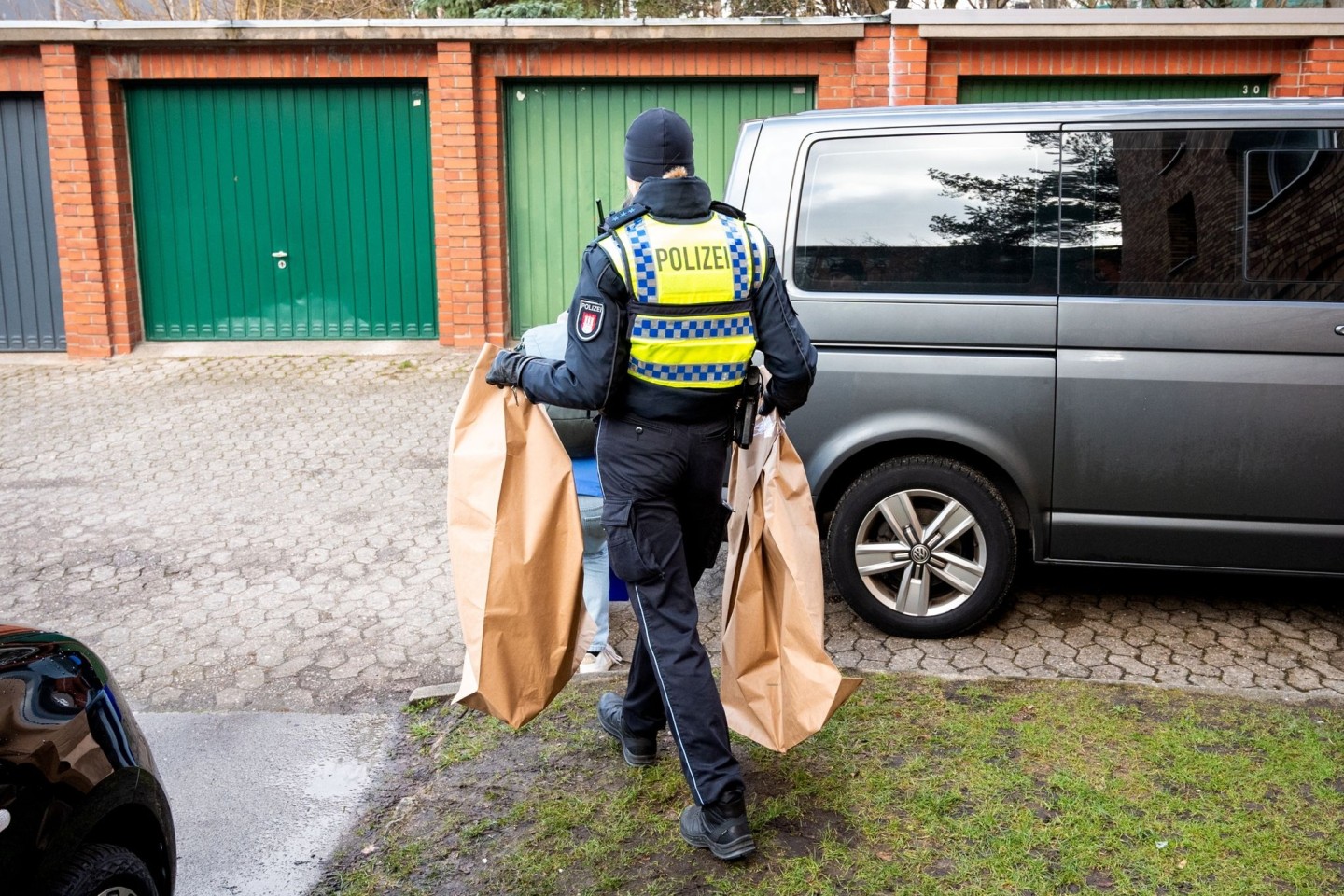 Eine Polizistin trägt Beweismittel aus einem Mehrfamilienhaus. Eine Hundertjährige soll dort von ihrem Enkel getötet worden sein.