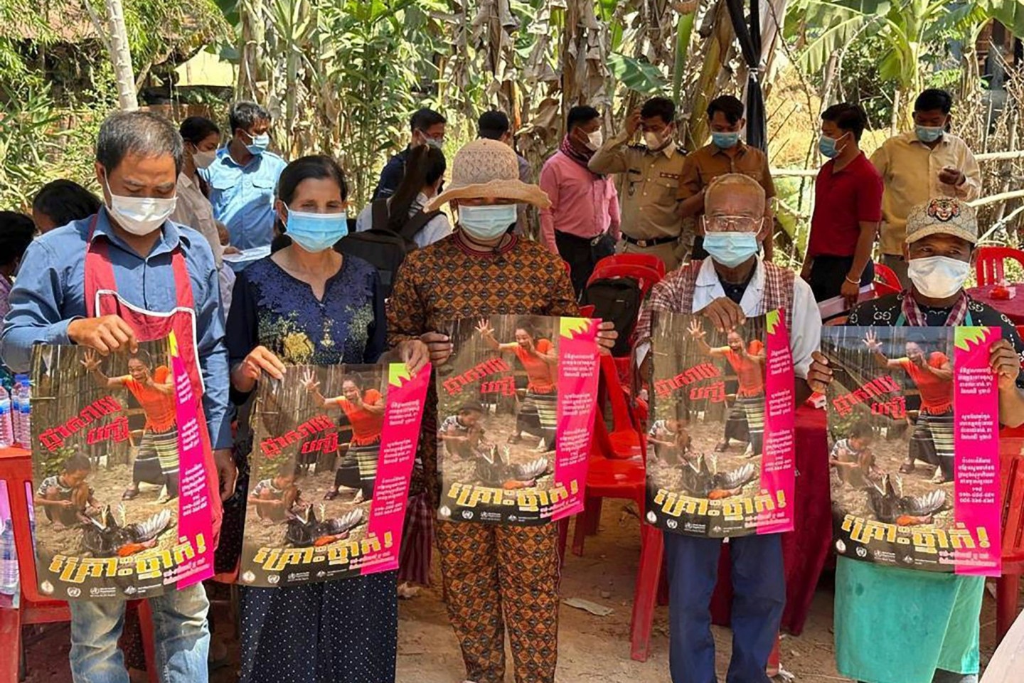 Dorfbewohner in der östlichen Provinz Prey Veng mit Plakaten, die auf die Bedrohung durch das Vogelgrippevirus aufmerksam machen.