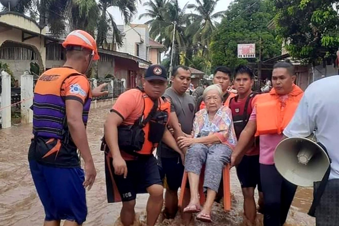 Eine ältere Frau wird von Mitarbeitern der Küstenwache in Sicherheit gebracht.