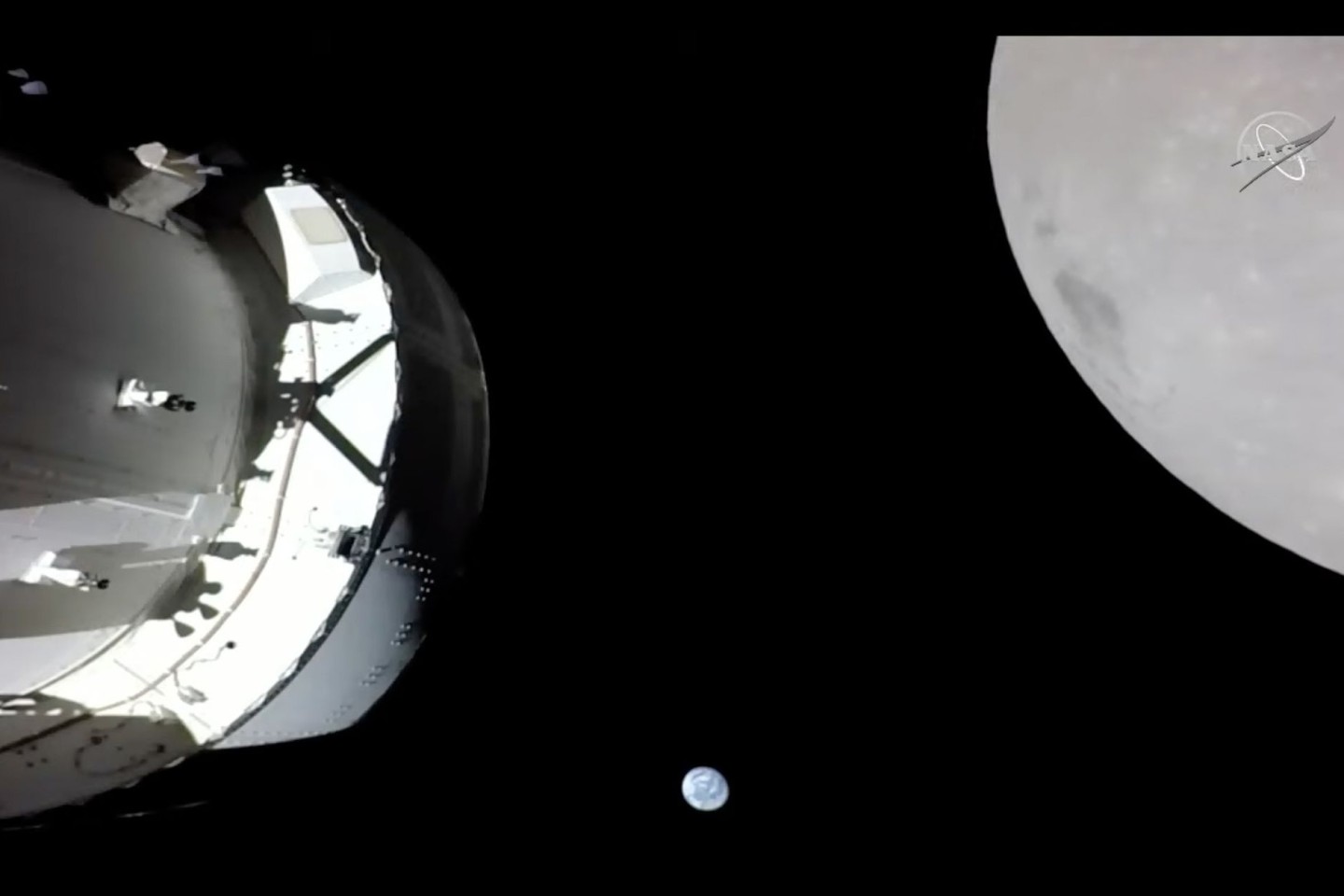 Eine Kamera an Bord der «Orion»-Kapsel zeigt das Raumschiff (l) im Weltraum, den Mond (r) und klein im Hintergrund die Erde.
