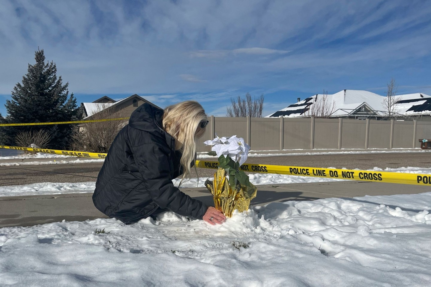 Eine Frau legt Blumen vor dem Haus ab, in dem acht Familienmitglieder tot aufgefunden wurden.
